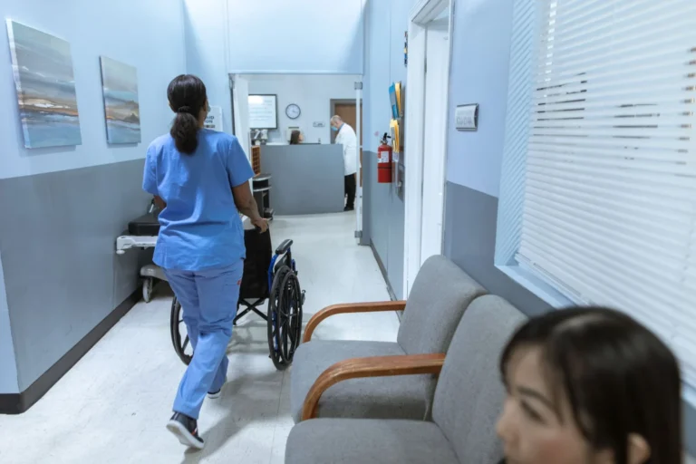 Enfermera con uniforme azul caminando por el pasillo de un hospital