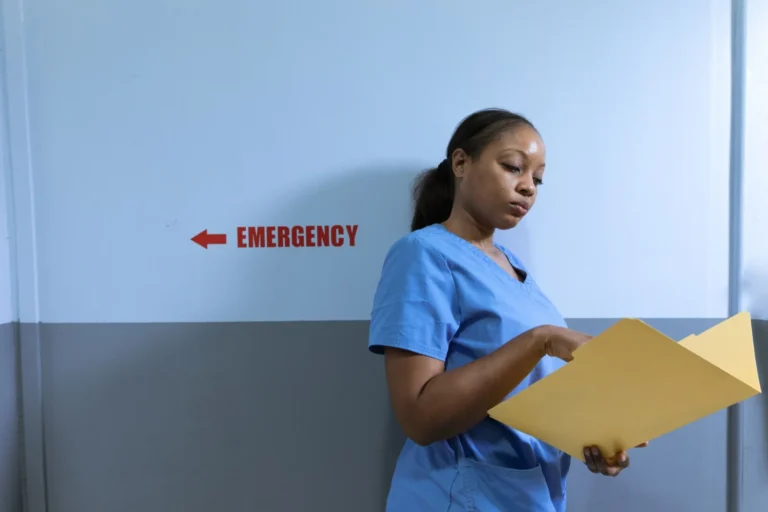 Enfermera con uniforme azul revisando un expediente en el hospital
