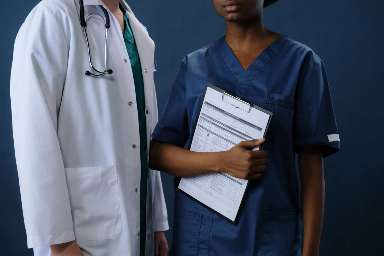 Dos profesionales de la salud revisando documentos con un portapapeles